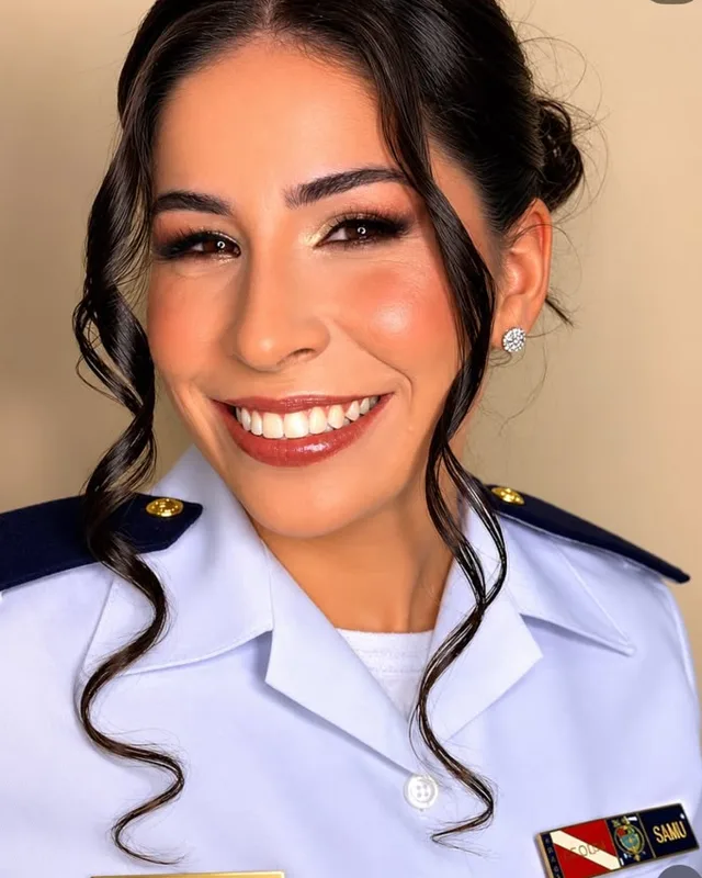 Formanda de uniforme branco sorrindo, com cachos presos