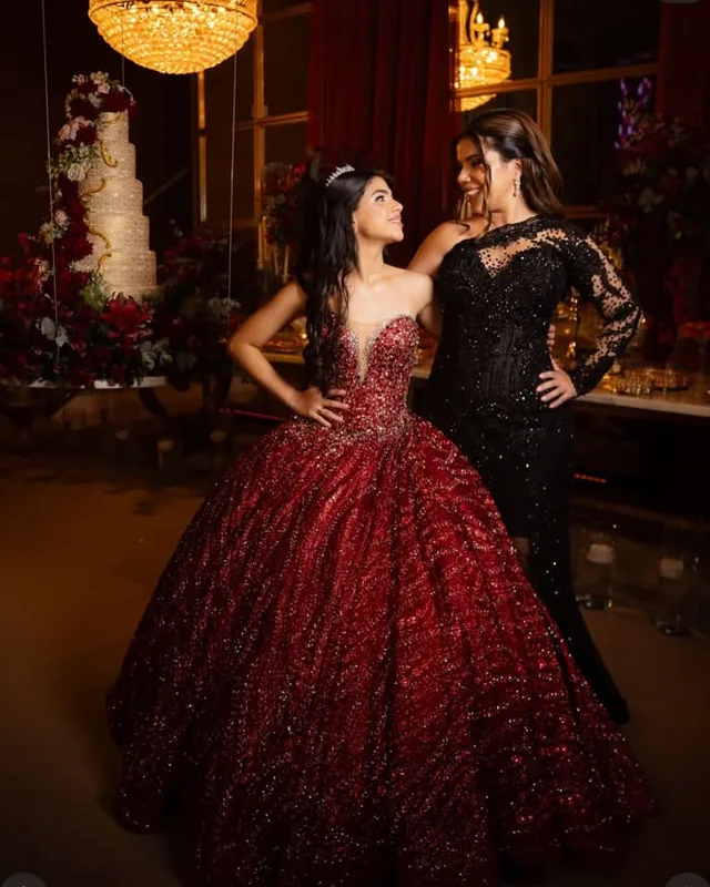 Debutantes de vestido vermelho e preto num salão com lustres