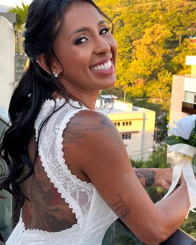 Noiva sorrindo, de vestido branco rendado nas costas