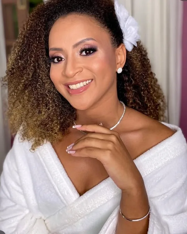 Noiva de cabelo cacheado com flor branca, sorrindo