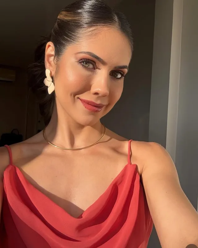 Convidada de vestido vermelho, cabelo preso e brincos dourados